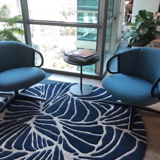 Blue armchairs on end table between them on blue and white rug