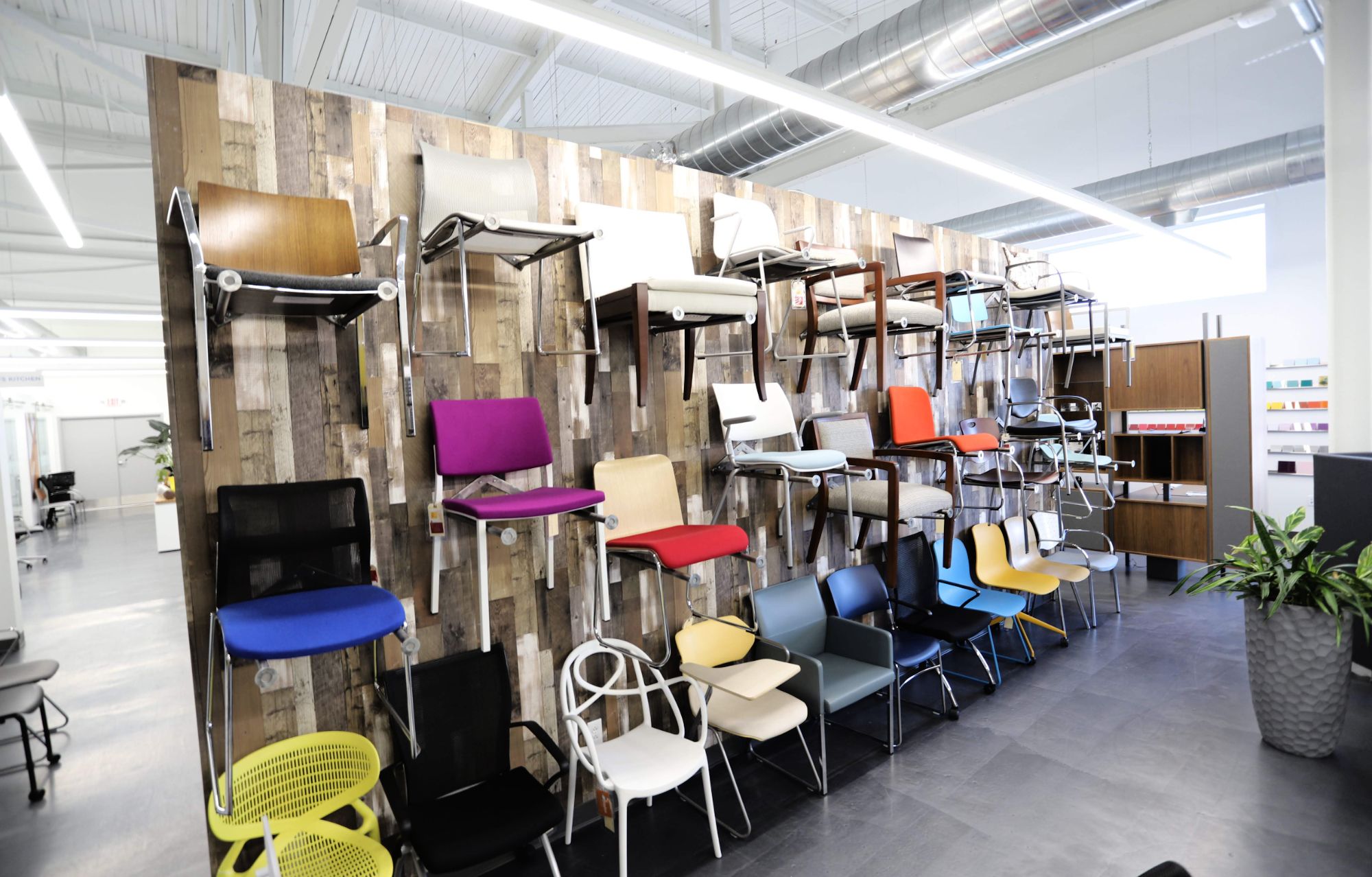 Various chairs in a variety of colors hanging on the showroom wall at CP Group