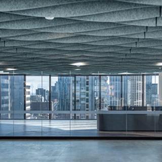 Ceiling acoustic baffle system in open space with windows showing city