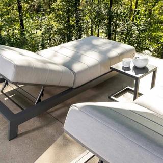Two gray sunbed with end table and forest background