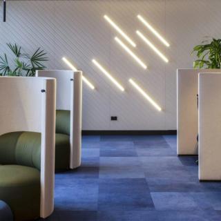 Router cut patterned panels on wall with diagonal lights on floor with blue carpting 