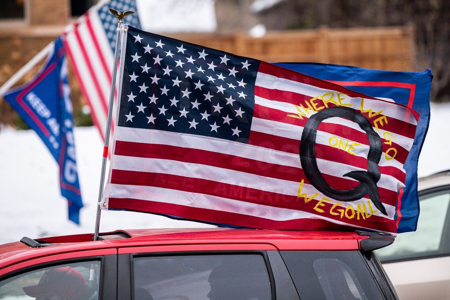 An American flag decorated with ‘When we go one we go all’ and a large ‘Q’.