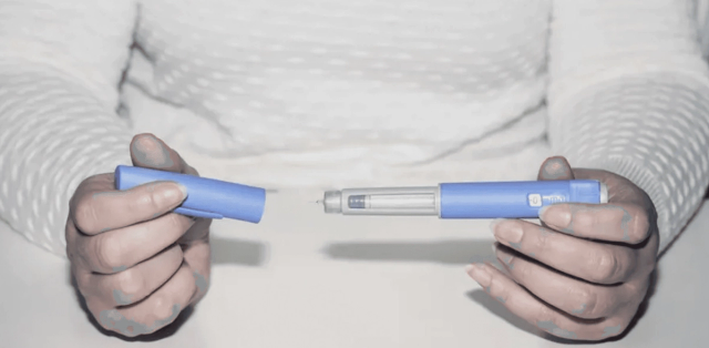 Person holding blue medical injector pen - Compounded Semaglutide Side Effects
