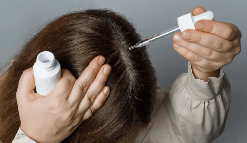 Person applying hair serum with a dropper - Does Semaglutide Cause Hair Loss