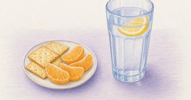 Crackers and orange on one side, water with lemon on the other.