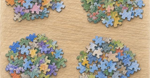 Loose jigsaw pieces pushed into separate piles on a wooden table, none connected