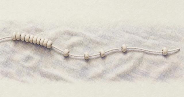 Cotton cord curving across linen with beads crowded at one end, spread at the other