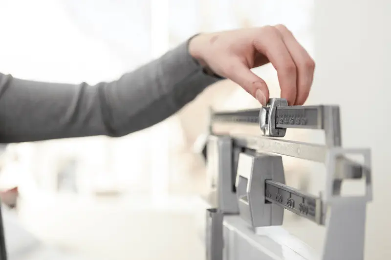 Hand adjusting weight on balance scale - How to Qualify for GLP-1