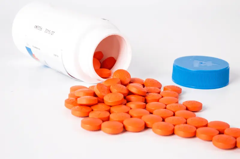 Orange pills spilling from white bottle - Titrating Medication Examples