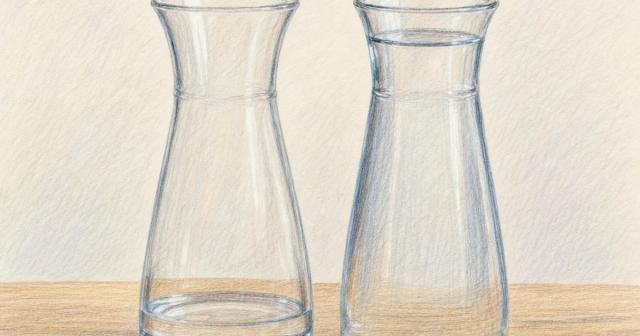 Two identical glass carafes side by side, one nearly empty and one filled to the top