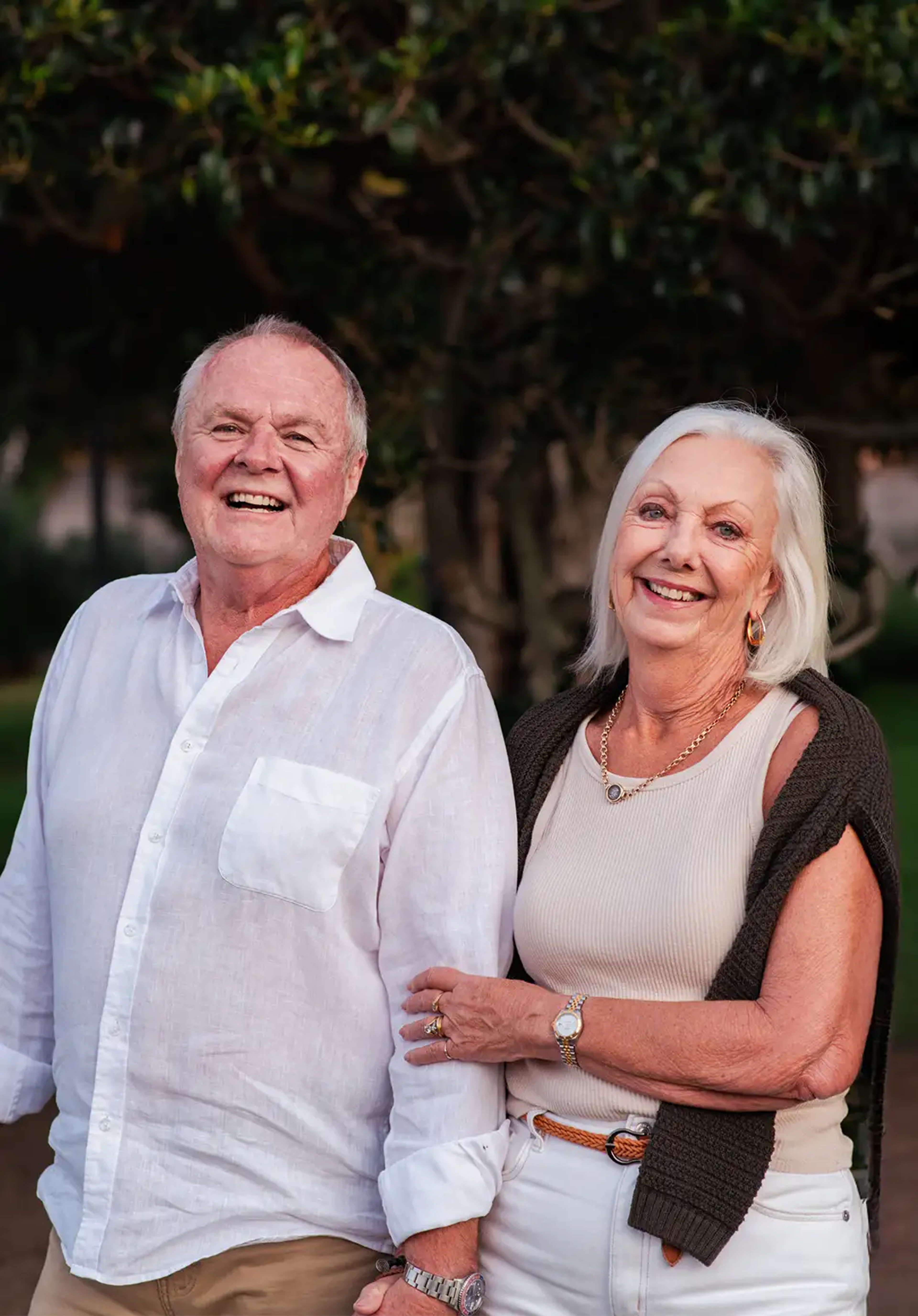 A happy, healthy couple outdoors, smiling. They are over 55 years old.