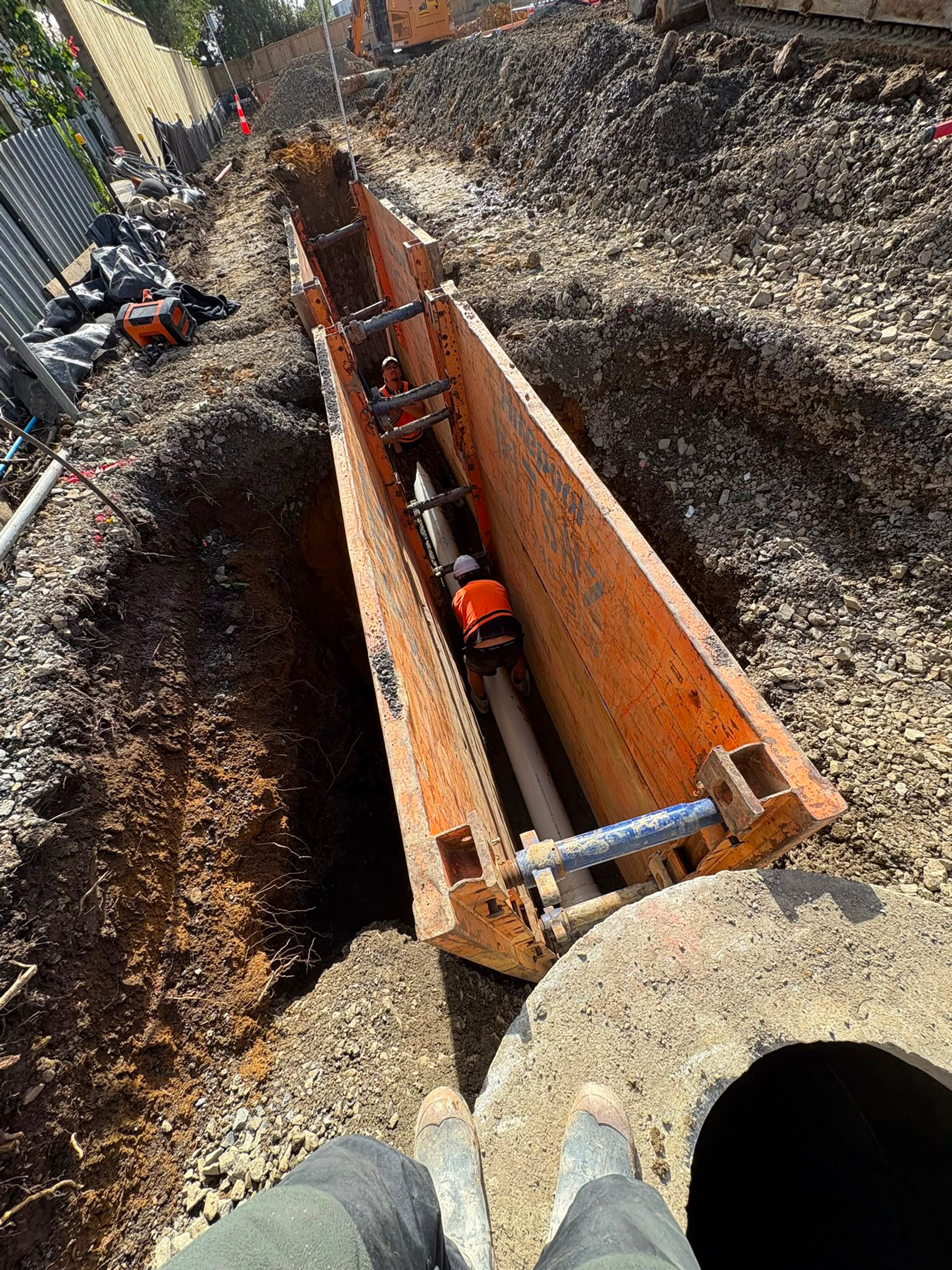 Trench shoring braced over a concrete pipe run in a deep excavation