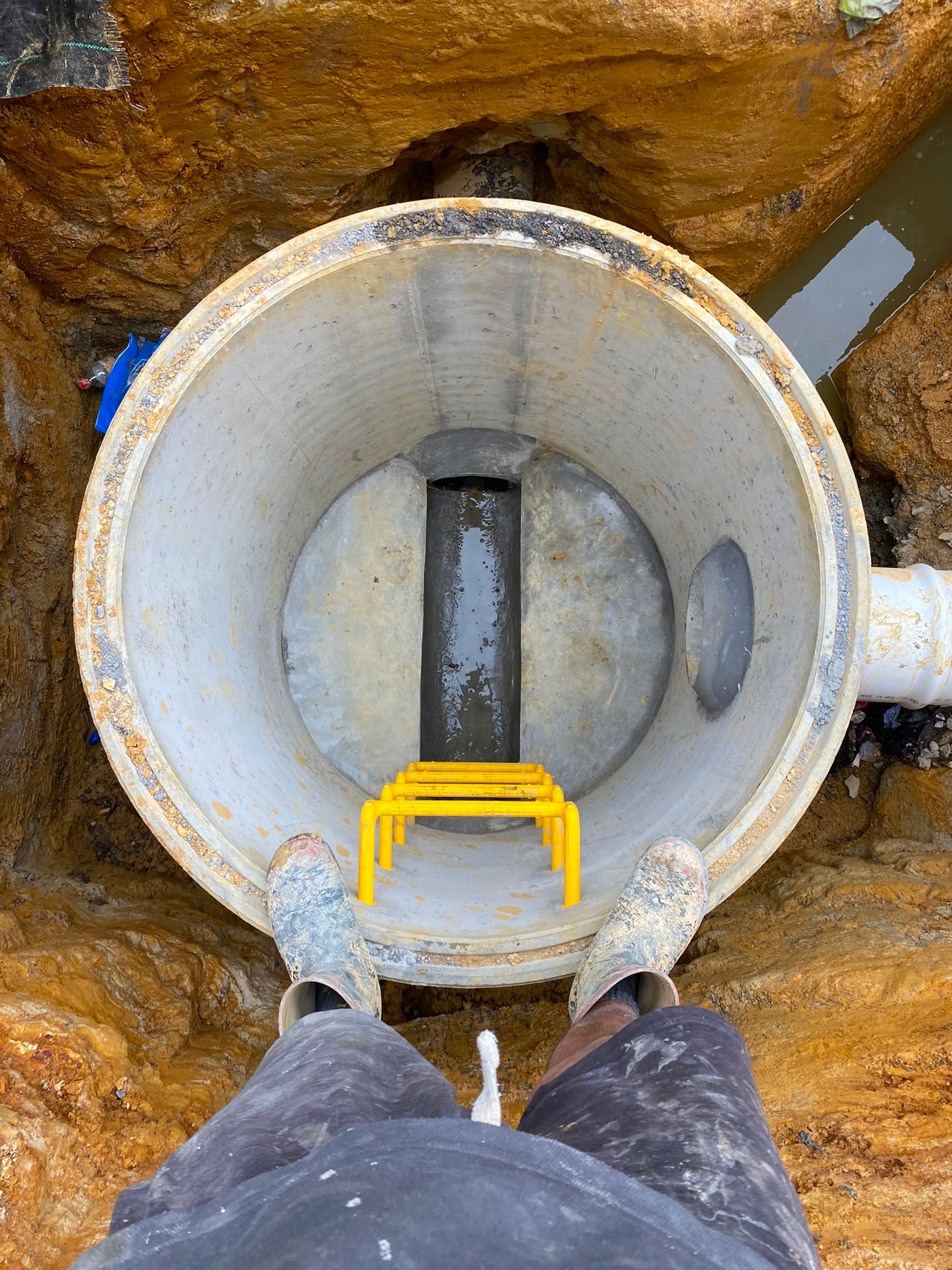Standing over a manhole chamber, looking down at the benched channel