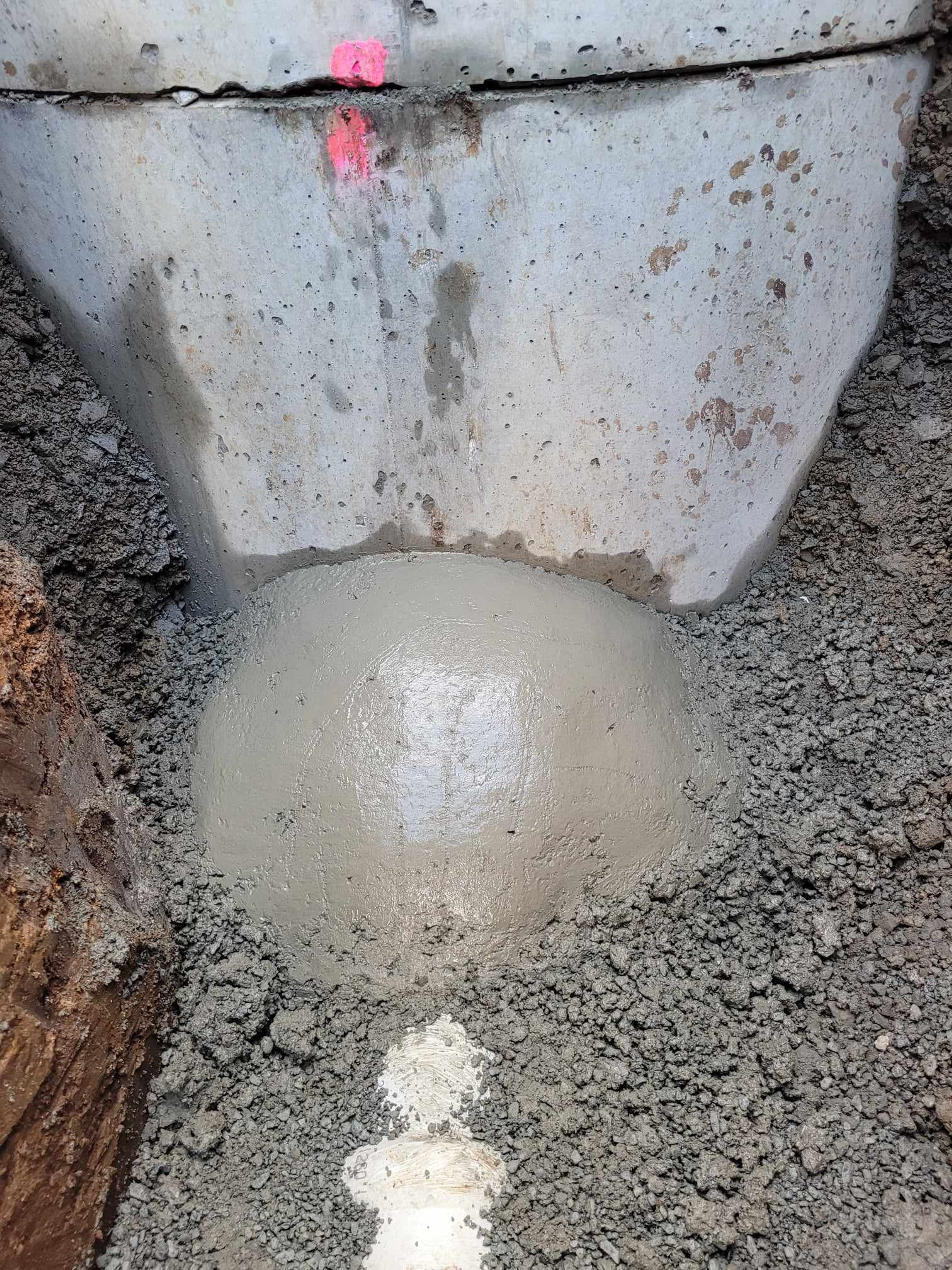 Concrete haunching poured around a pipe where it enters a chamber base