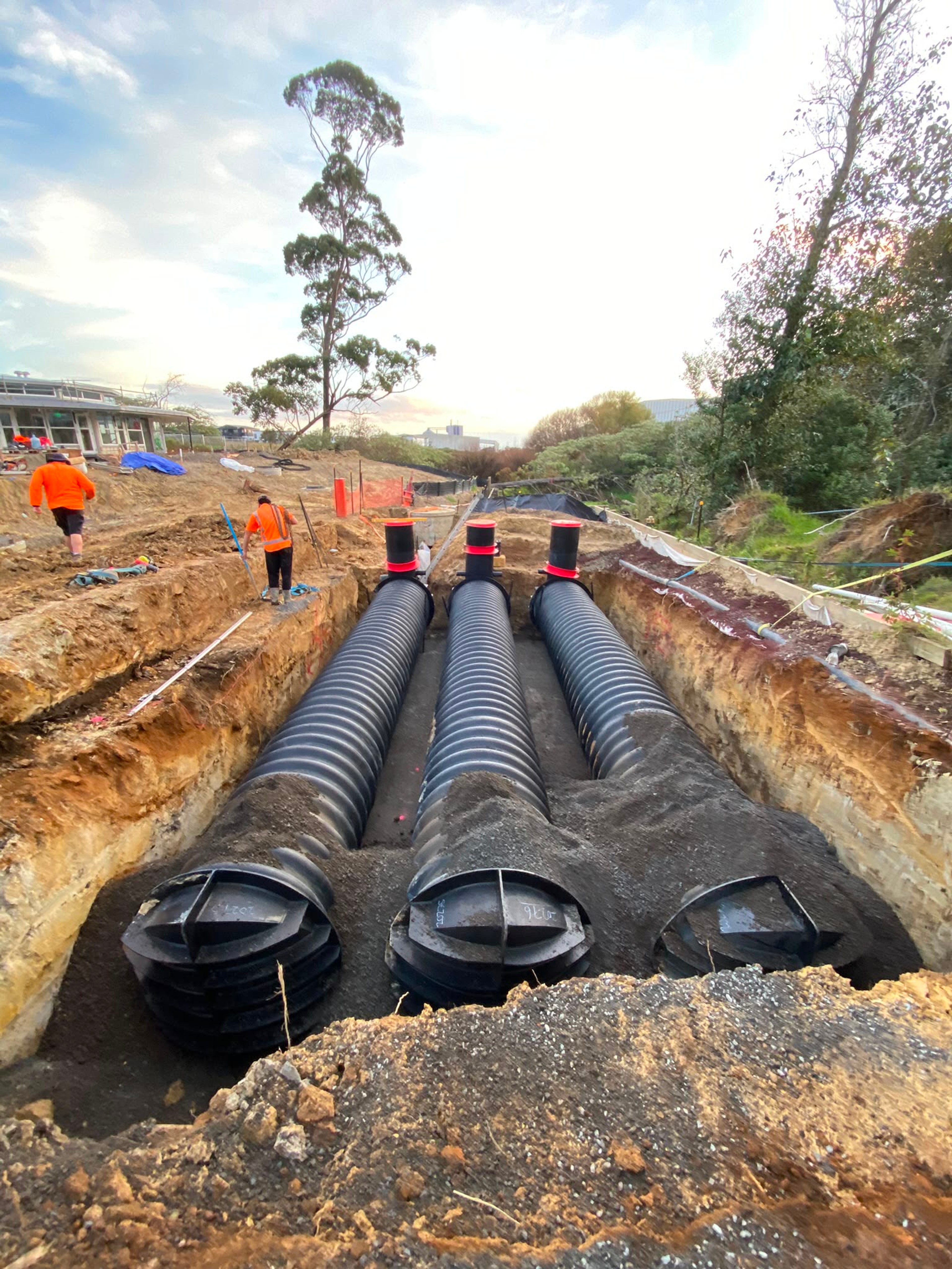 Three large stormwater chambers laid side by side in an open trench