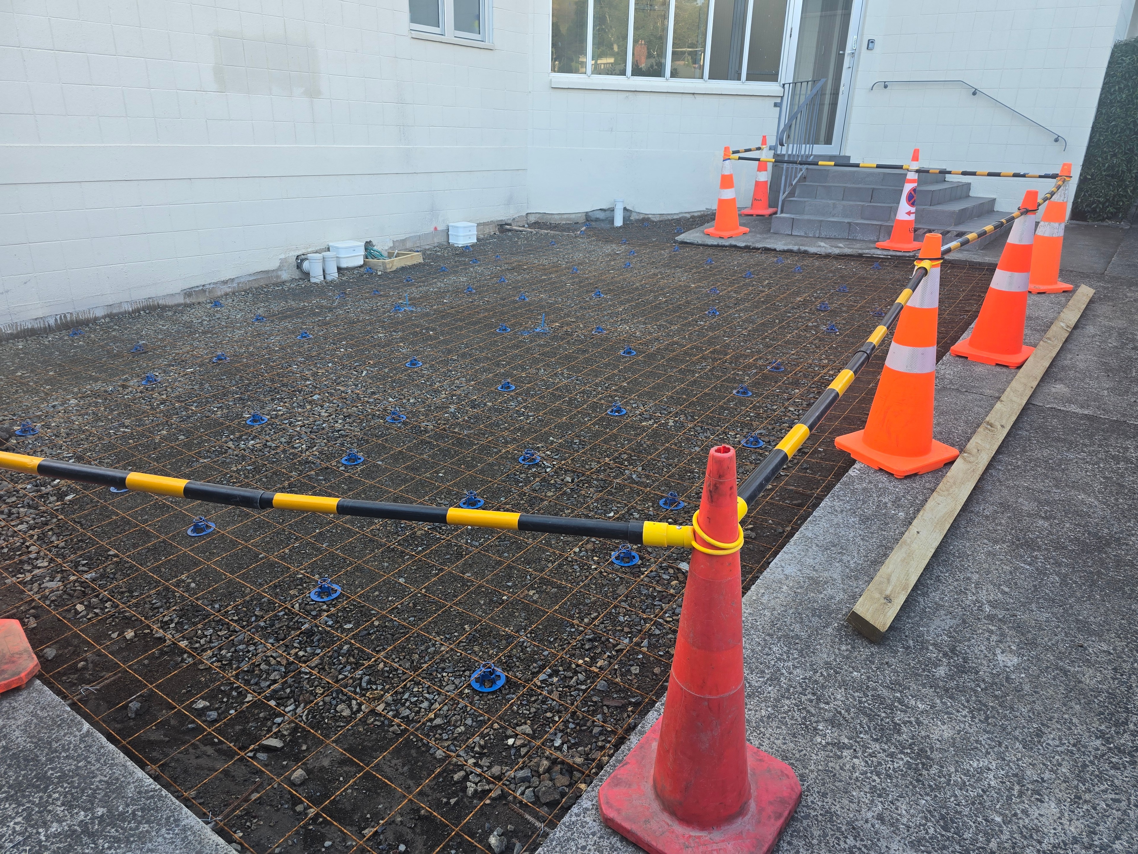 Steel reinforcing mesh set on spacers across a prepared area, boxed and ready for the pour