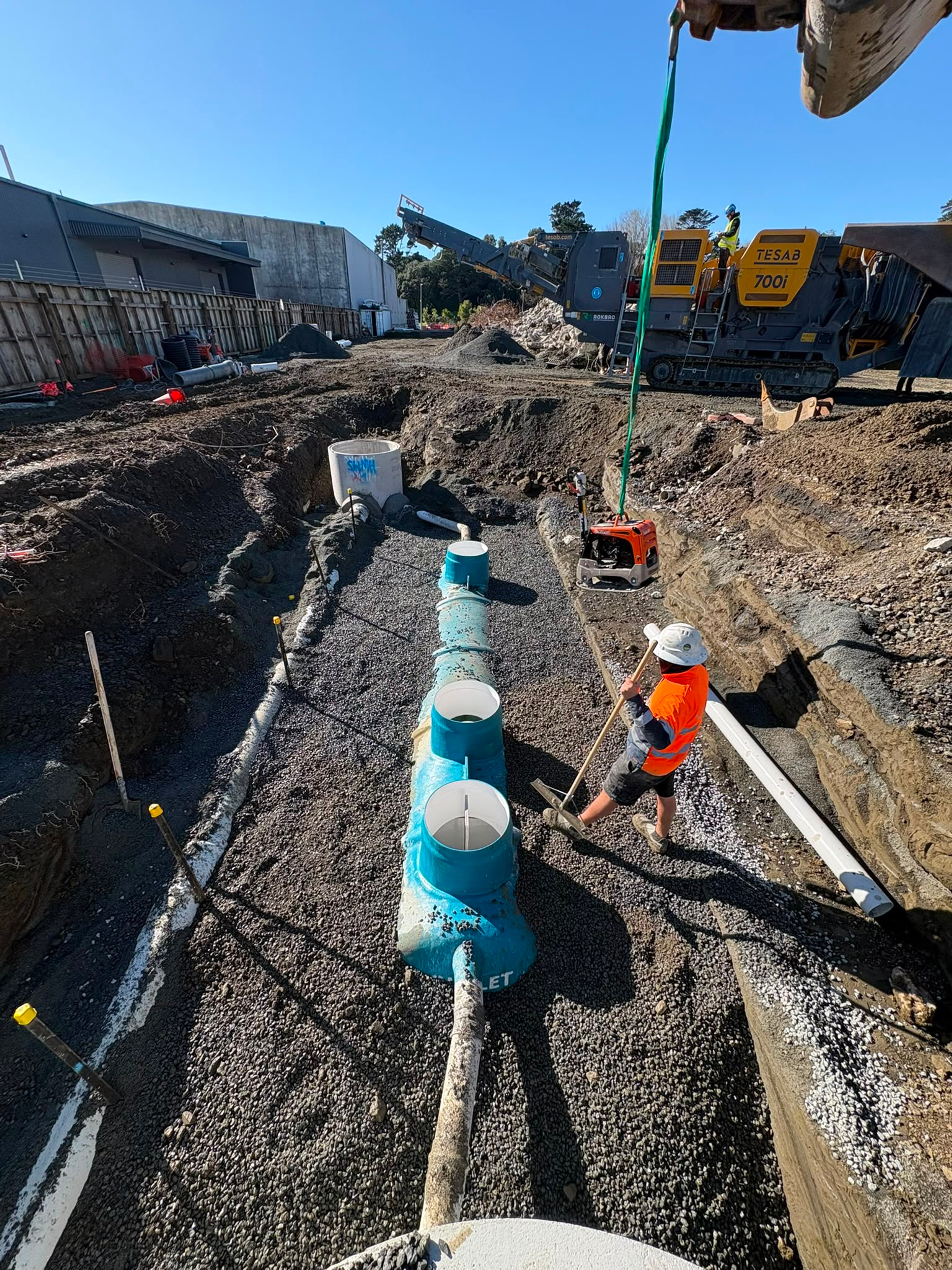 Worker connecting large stormwater fittings in an open trench
