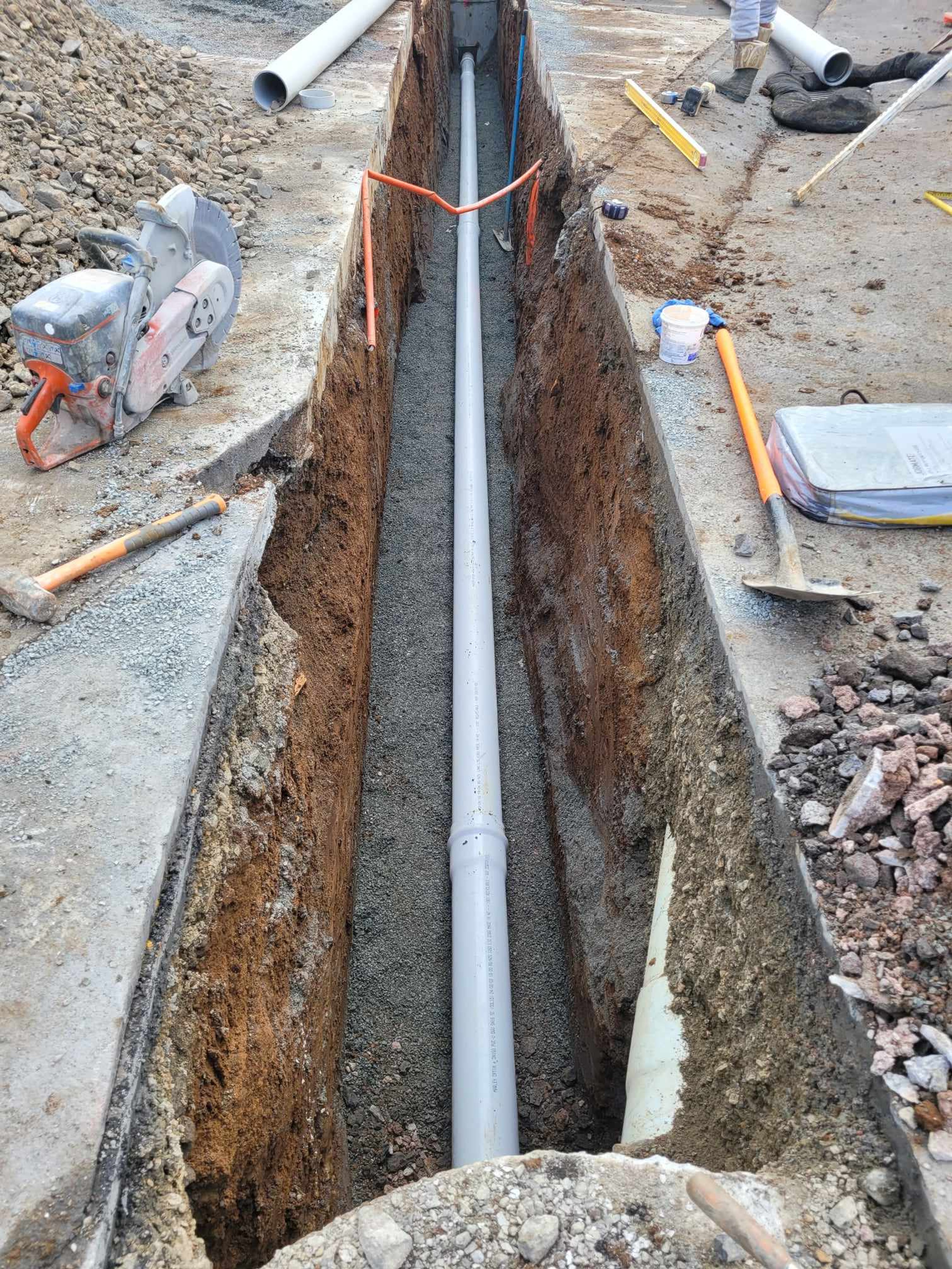 Stormwater pipe laid on bedding in a saw-cut trench through an existing concrete surface