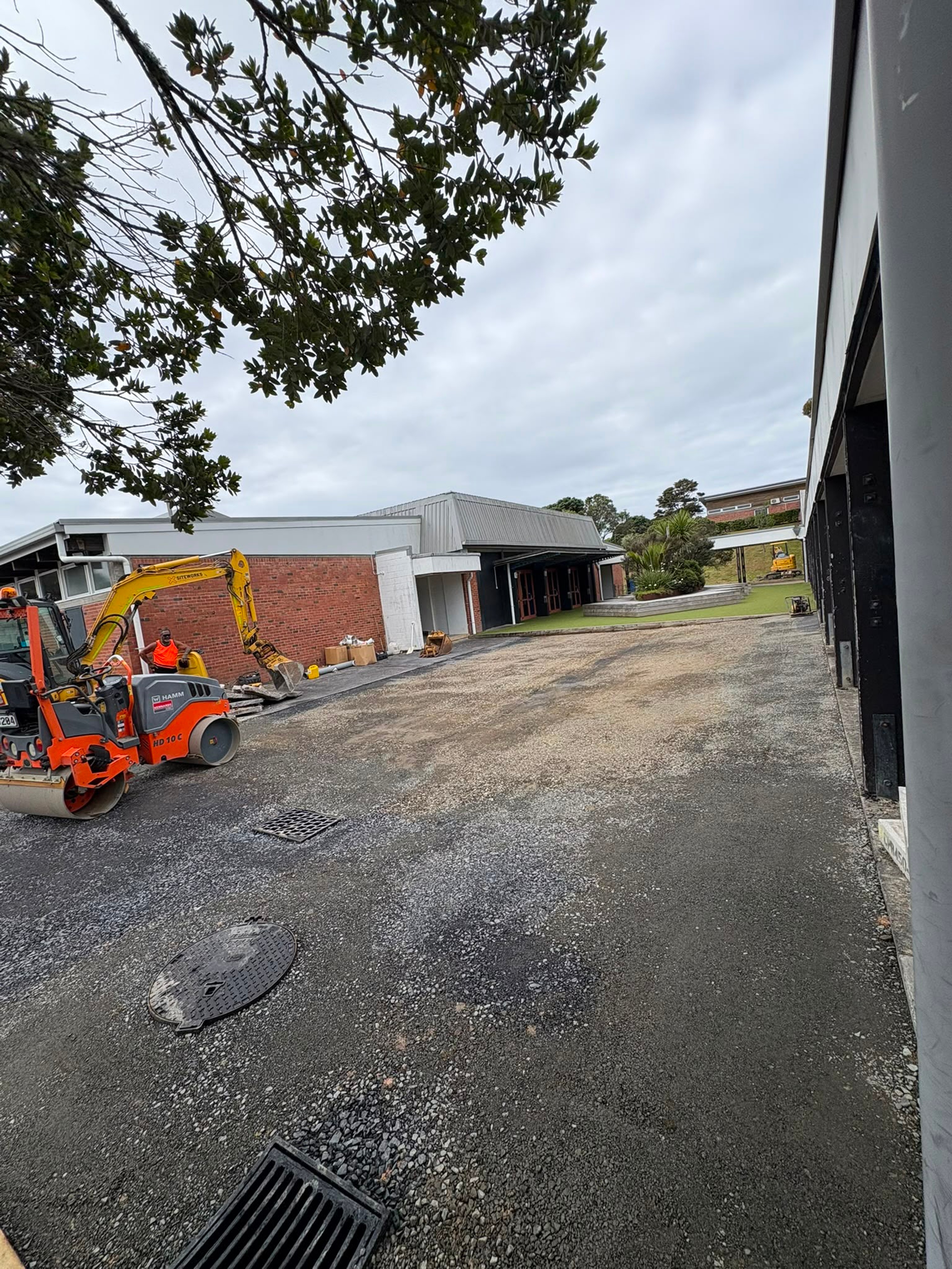 Roller and excavator preparing a driveway at a school
