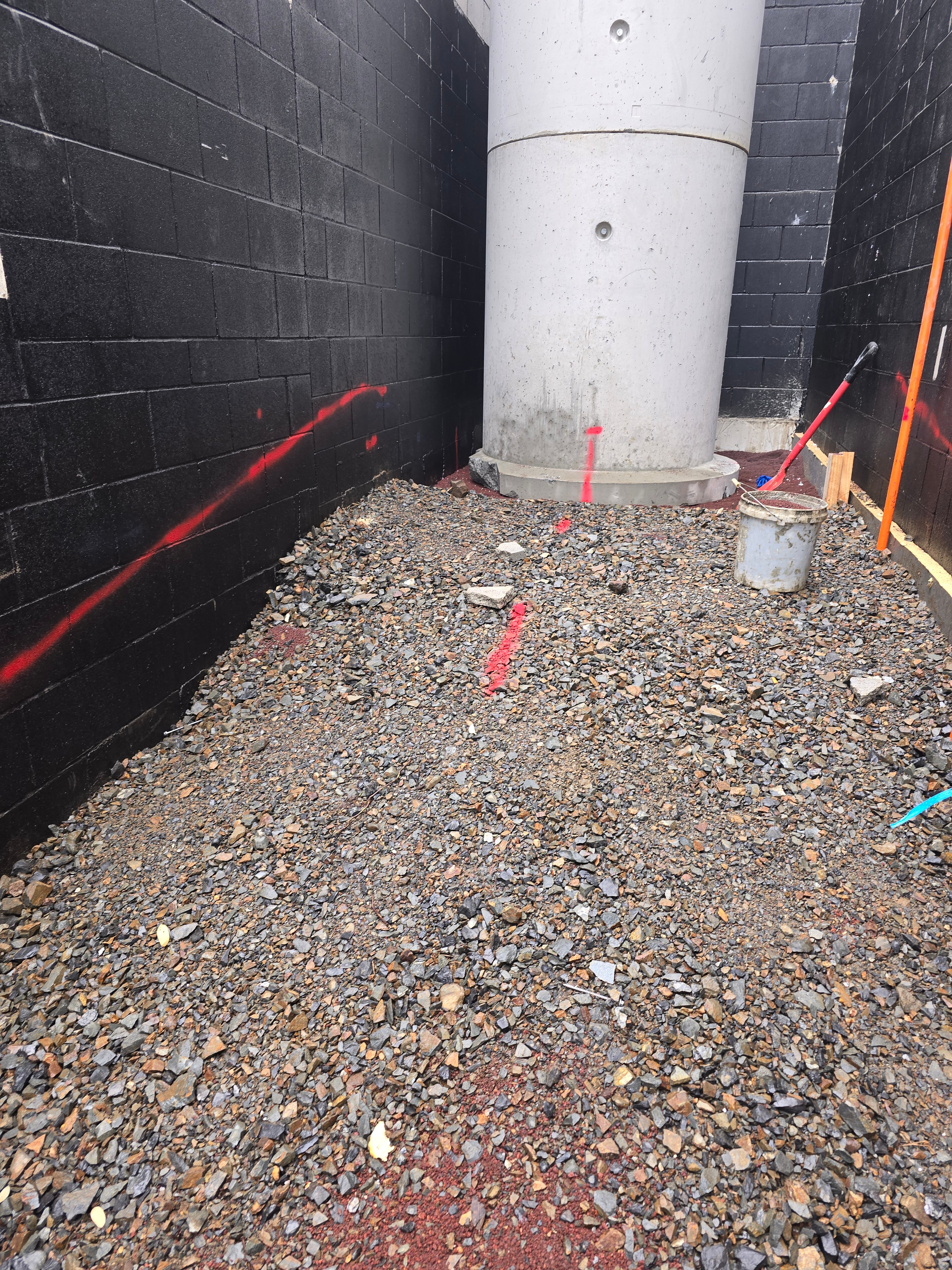 Base of a concrete manhole riser backfilled with drainage metal between blockwork walls