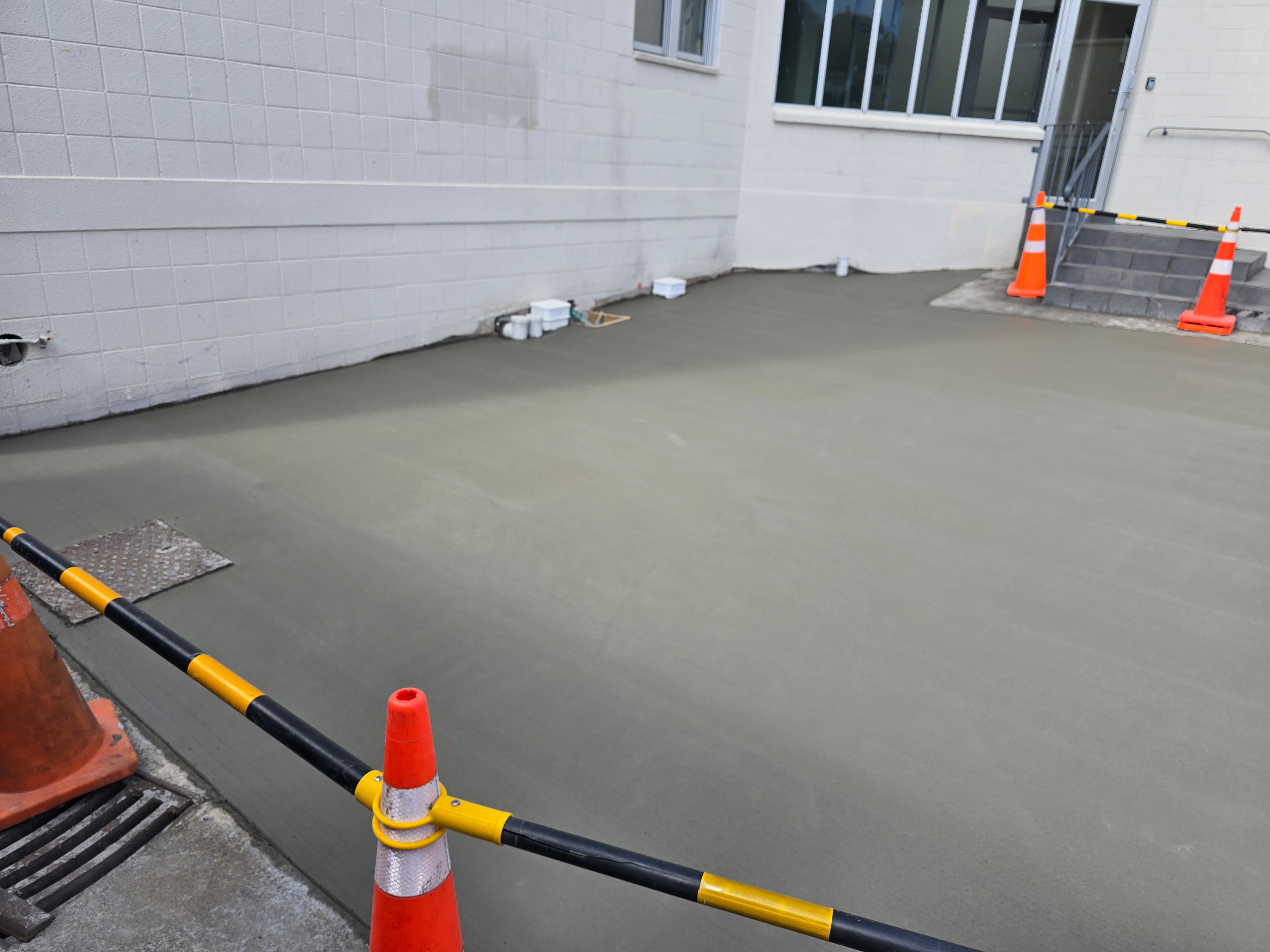 Freshly poured and floated concrete slab, cordoned off to cure