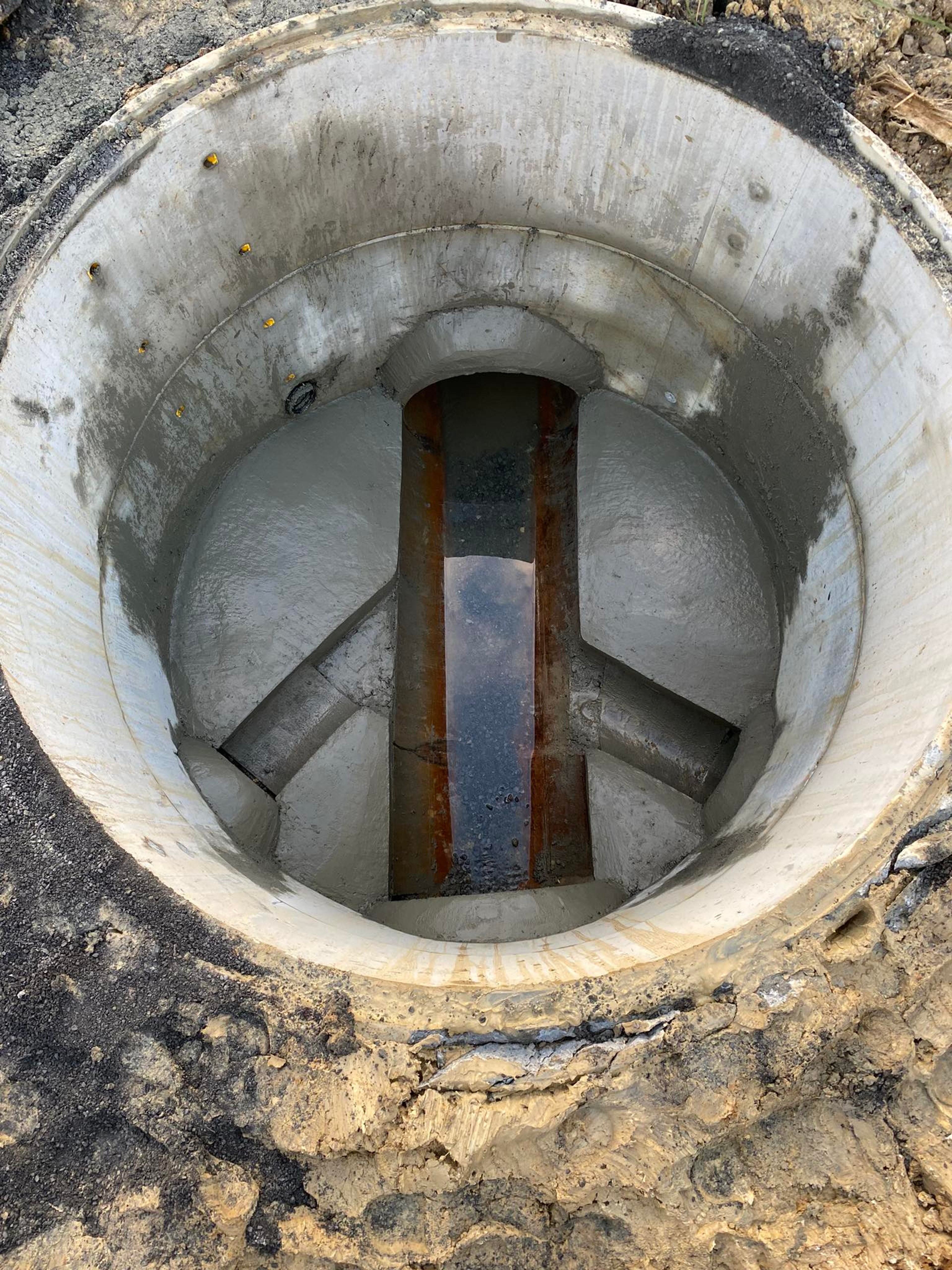Looking down a finished manhole chamber at the benched concrete channel