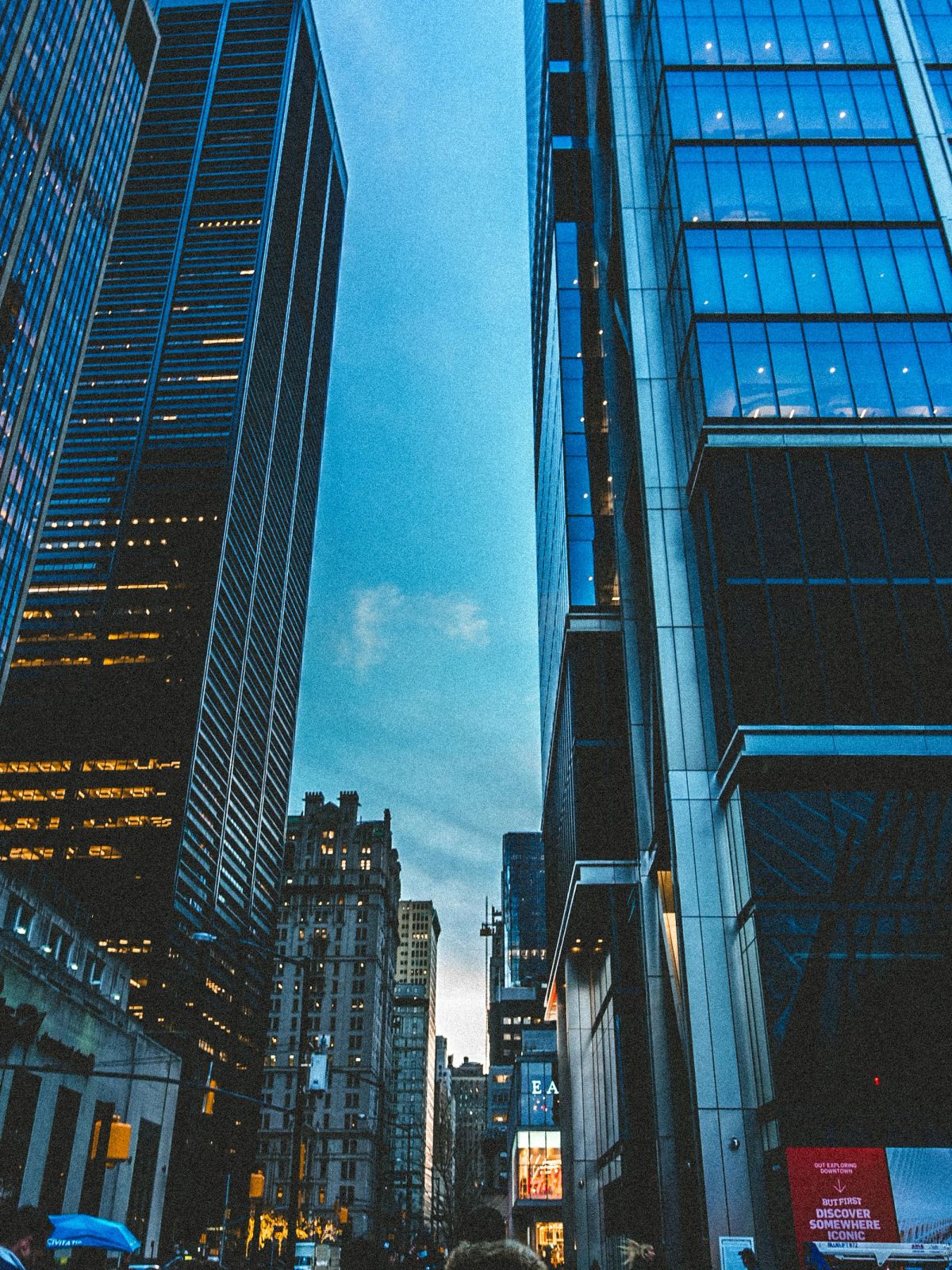 Looking up between blue glass towers at dusk