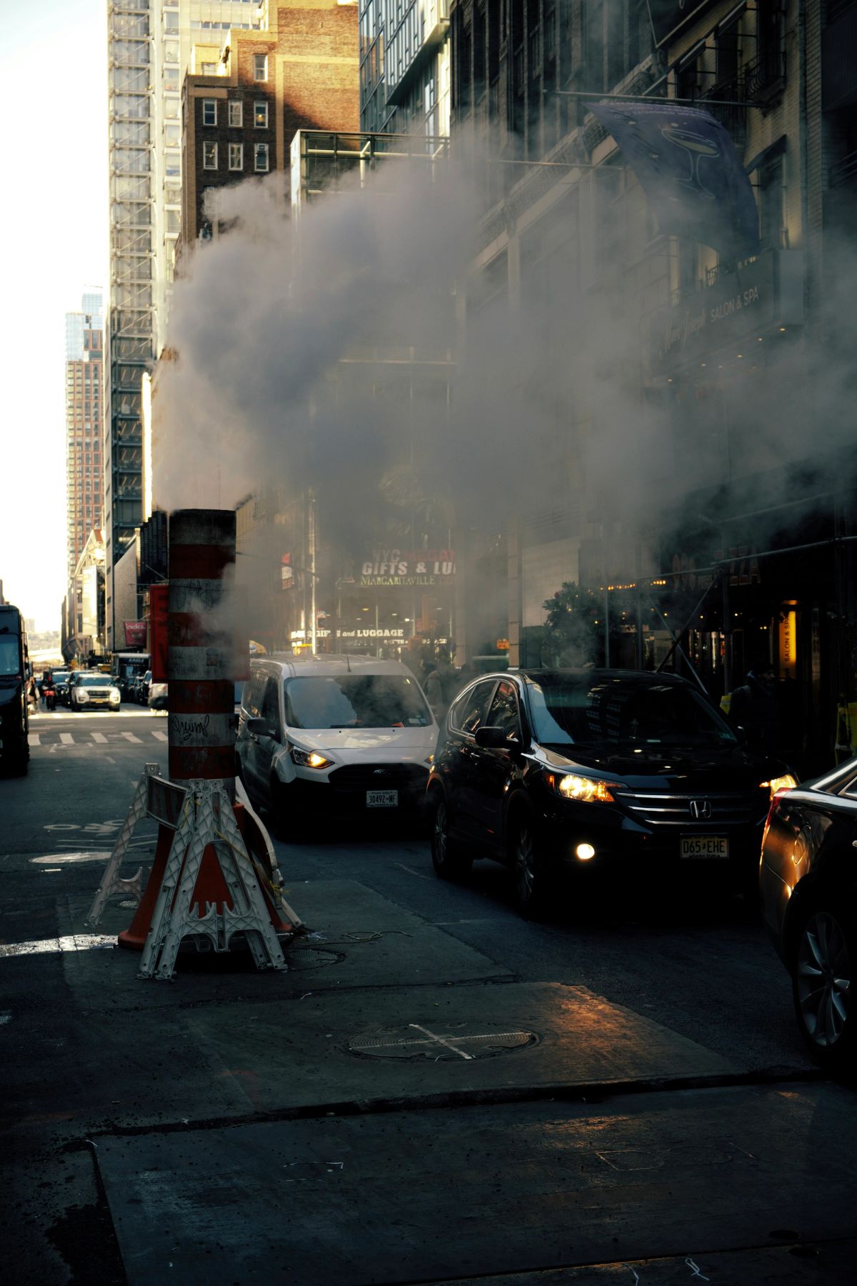 Steam pouring from an orange and white vent stack into Midtown traffic