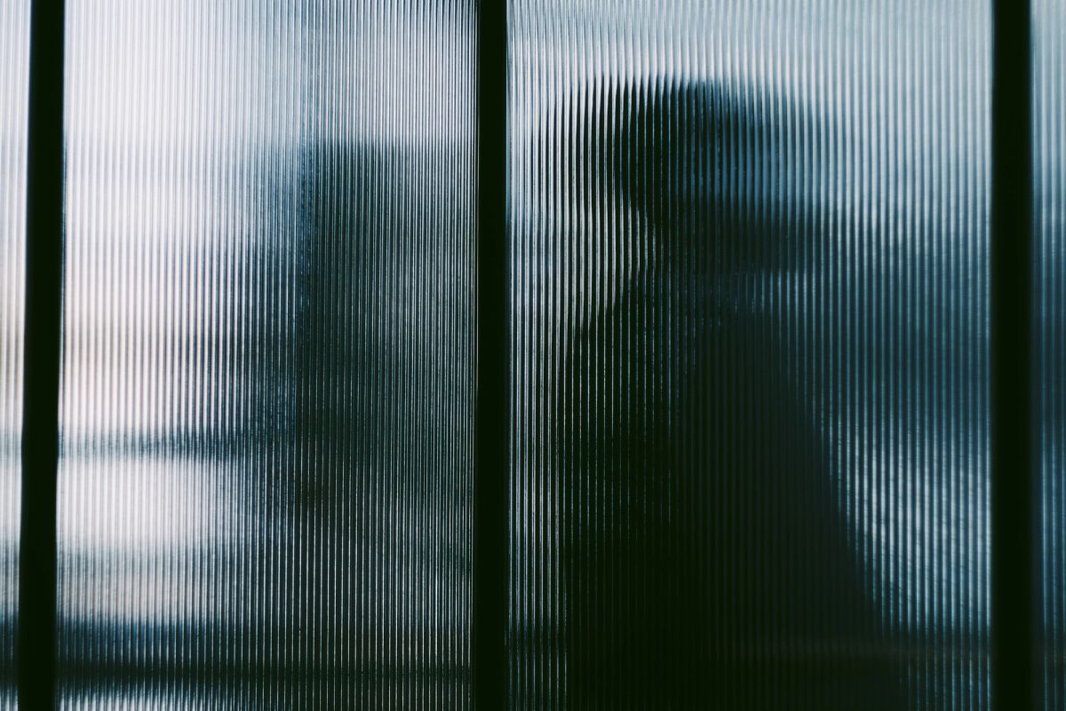Silhouettes of passers-by behind ribbed glass panels