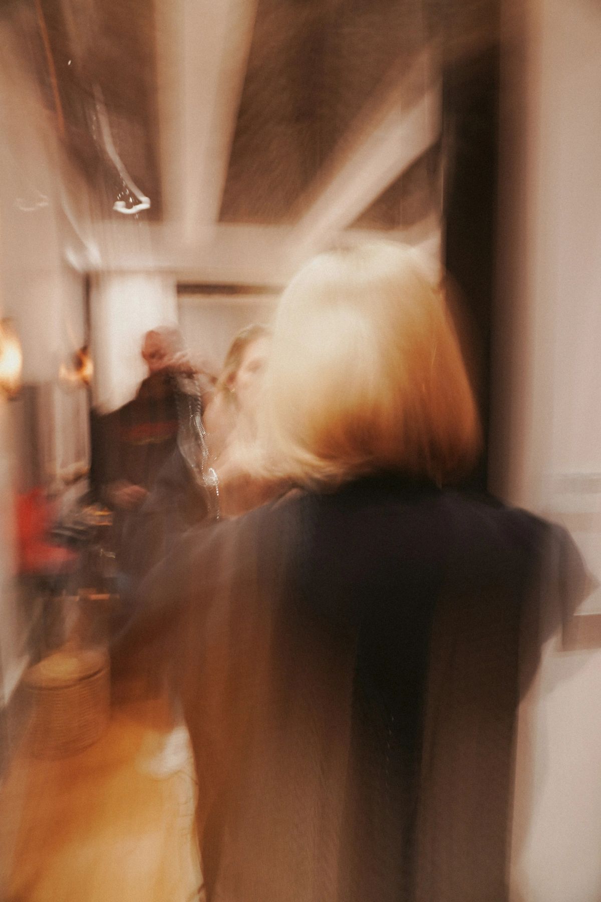 A blonde woman blurred into amber streaks as she walks past