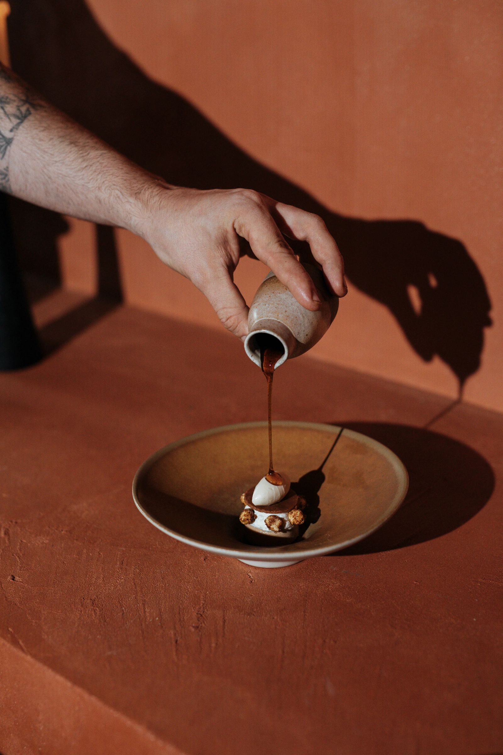 Saus die over een gerecht wordt gegoten op een terracotta tafel