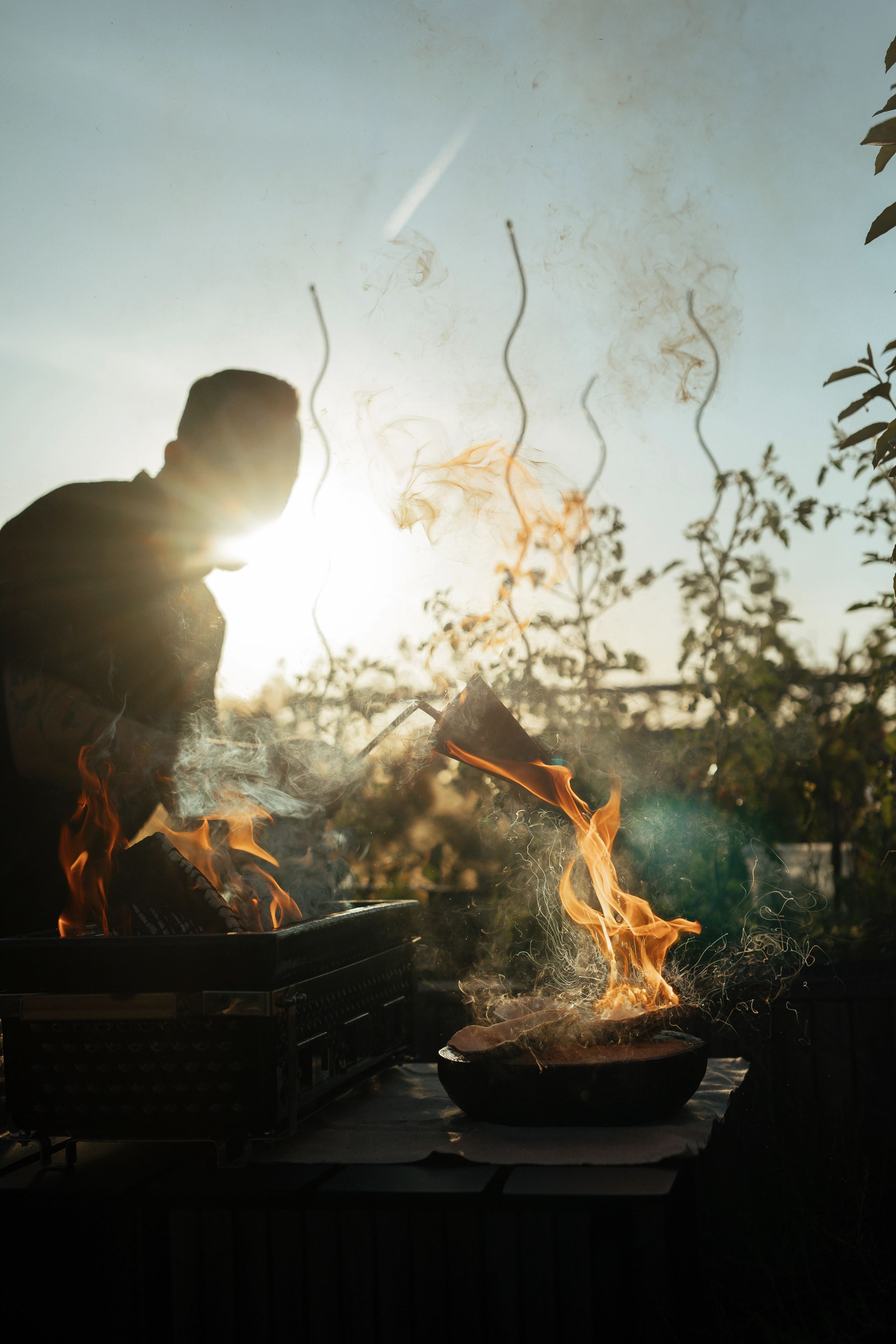 Een chef kookt op open vuur, in het tegenlicht van de ondergaande zon