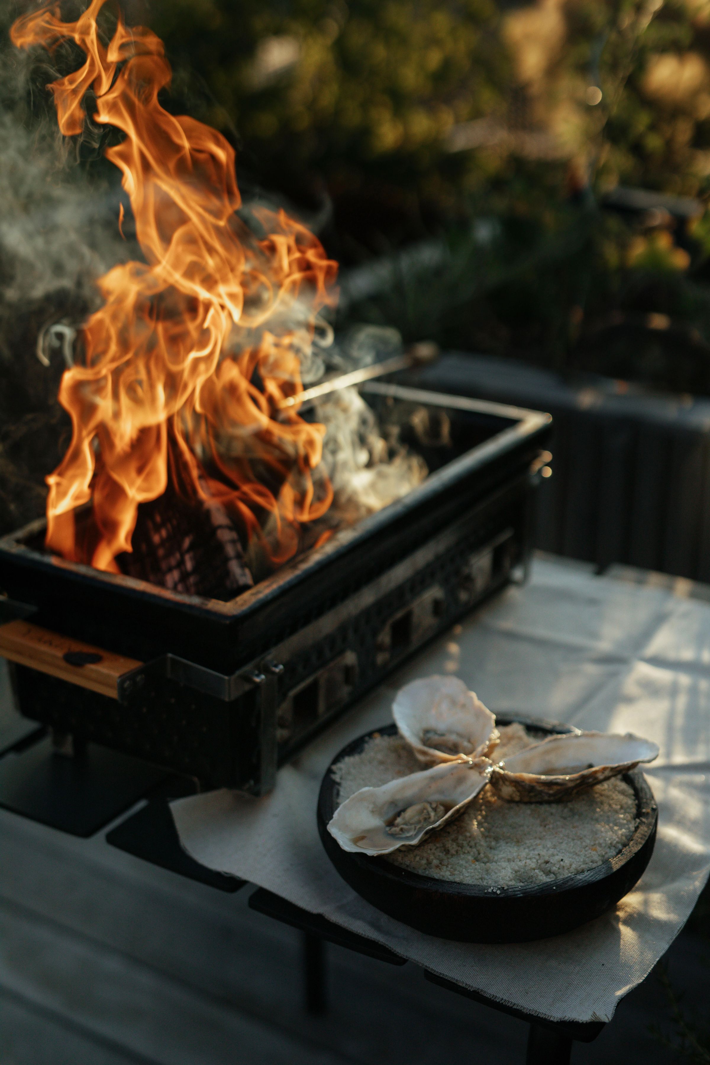 Vlammen uit een grill naast een gerecht op een tafel buiten