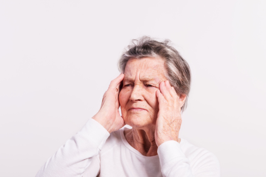 Tinnitus nedeniyle baş ağrısı ve rahatsızlık yaşayan yaşlı bir kadın – kulak çınlamasının yaşam kalitesine etkisi.