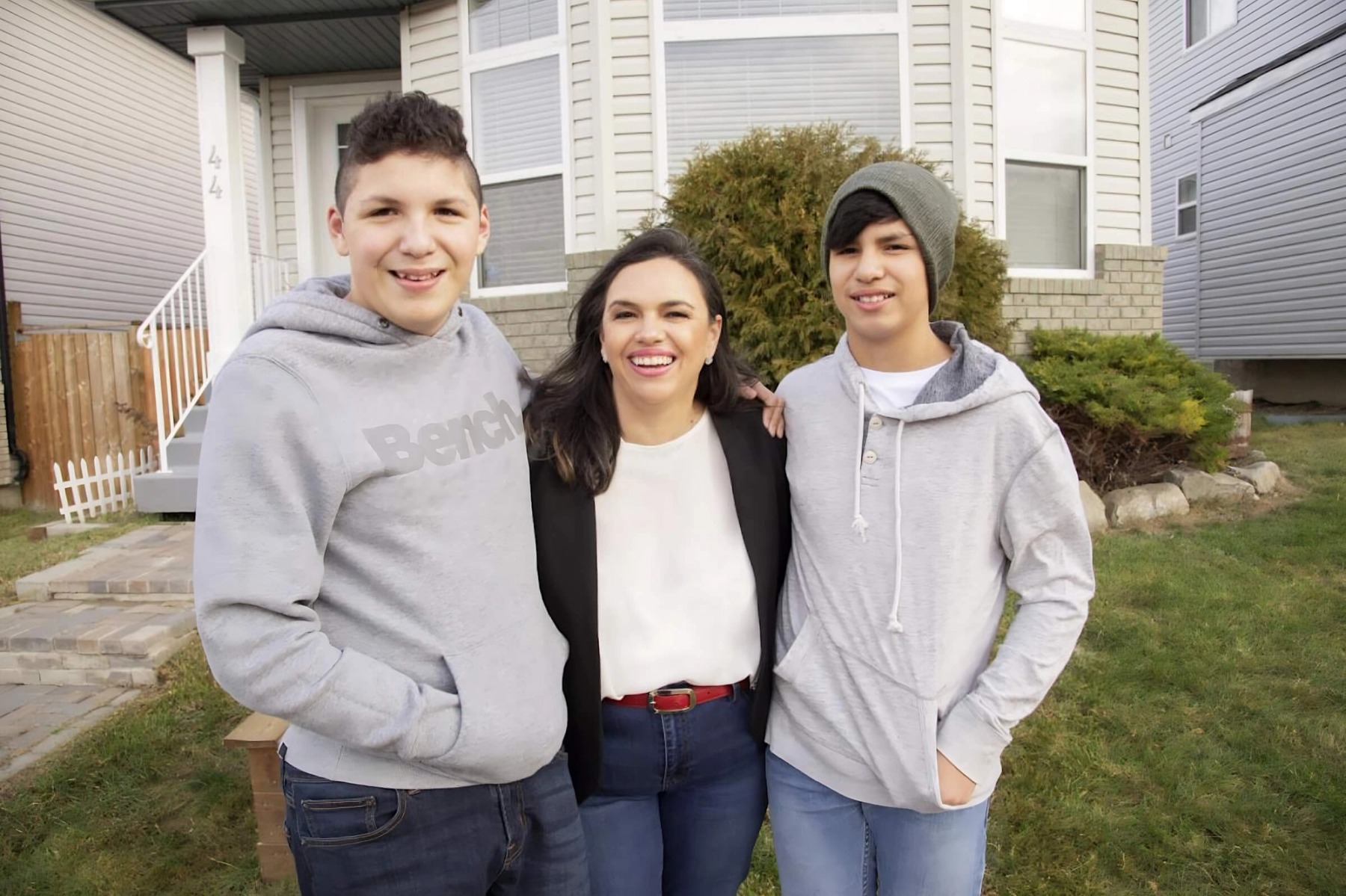 Rocio Martinez and her family stand in front of a home with green grass