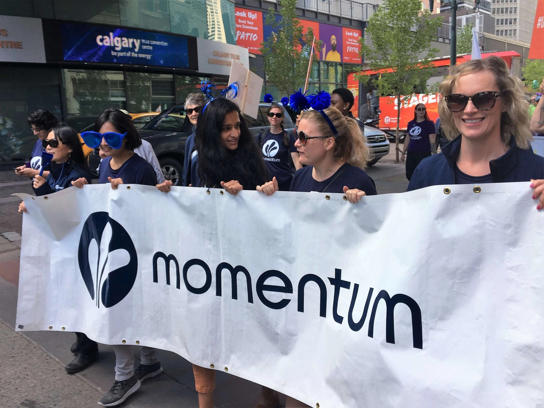 Staff and volunteers walking together, holding a "Momentum" banner, during the 2019 United Way Parade