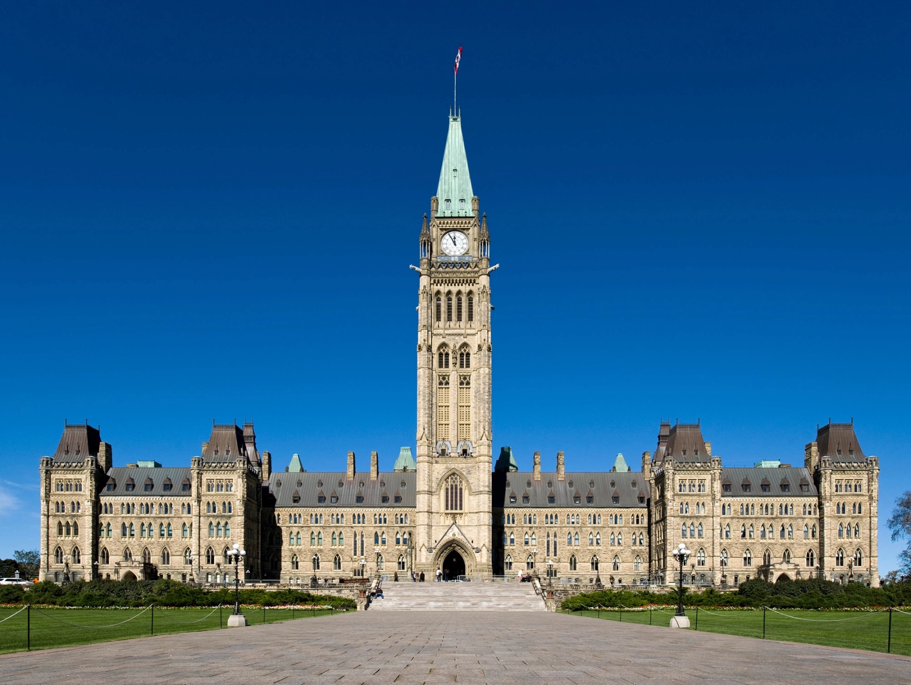 The Canadian Federal Parliament Building with a blue sky and green grass lawn.