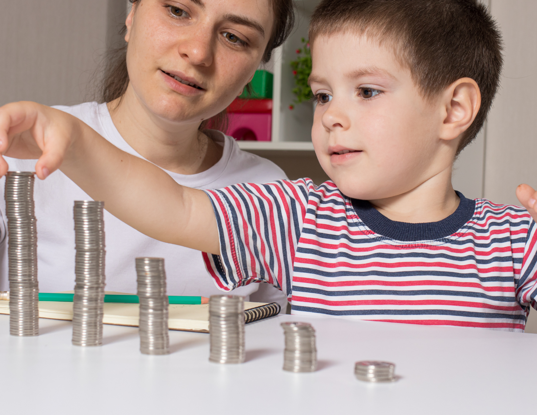 A woman and a child stack coins on a tabletop.