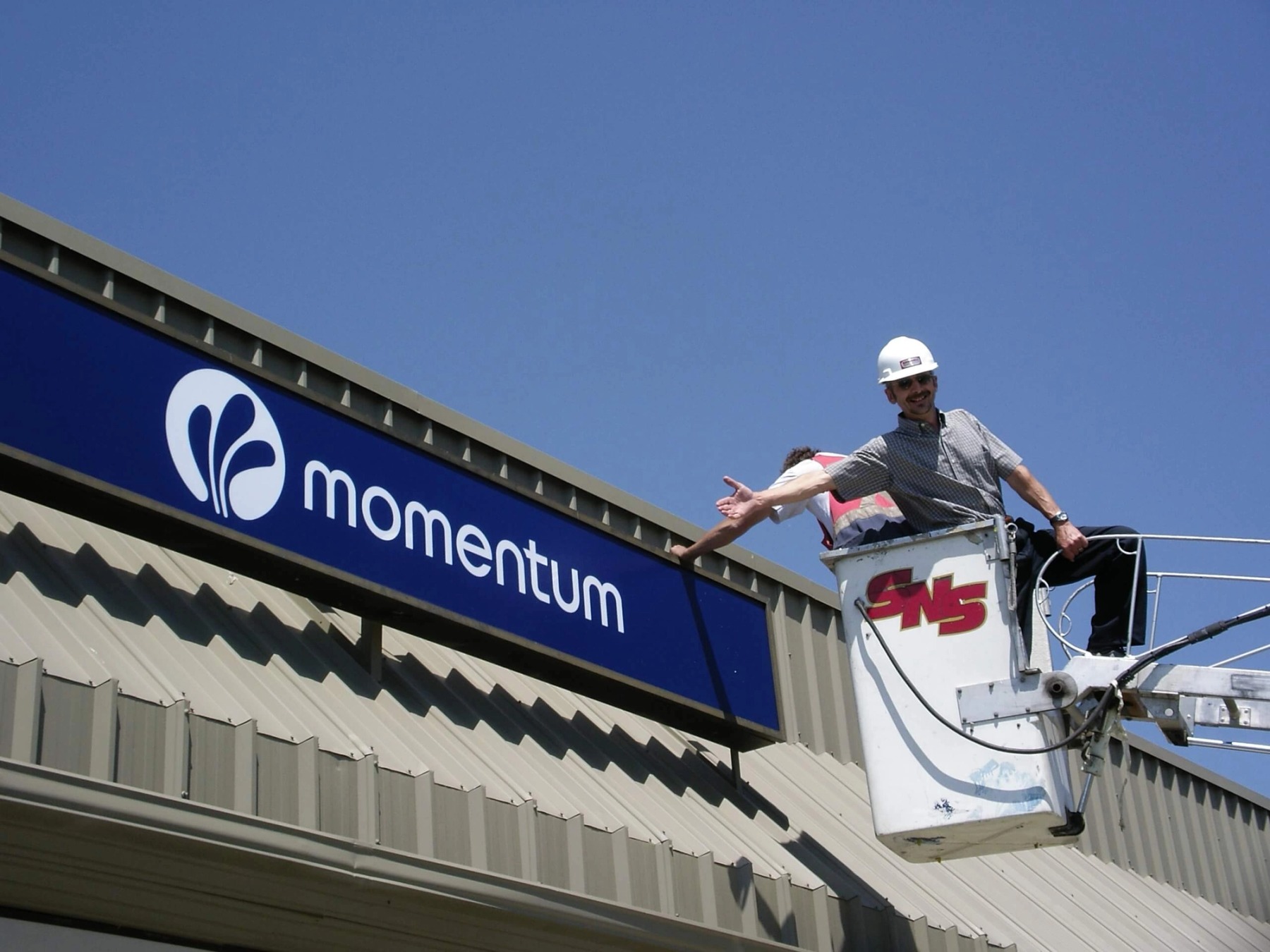 A worker in a hard hat gives a thumbs-up to new signage that's gone up at the Momentum building.