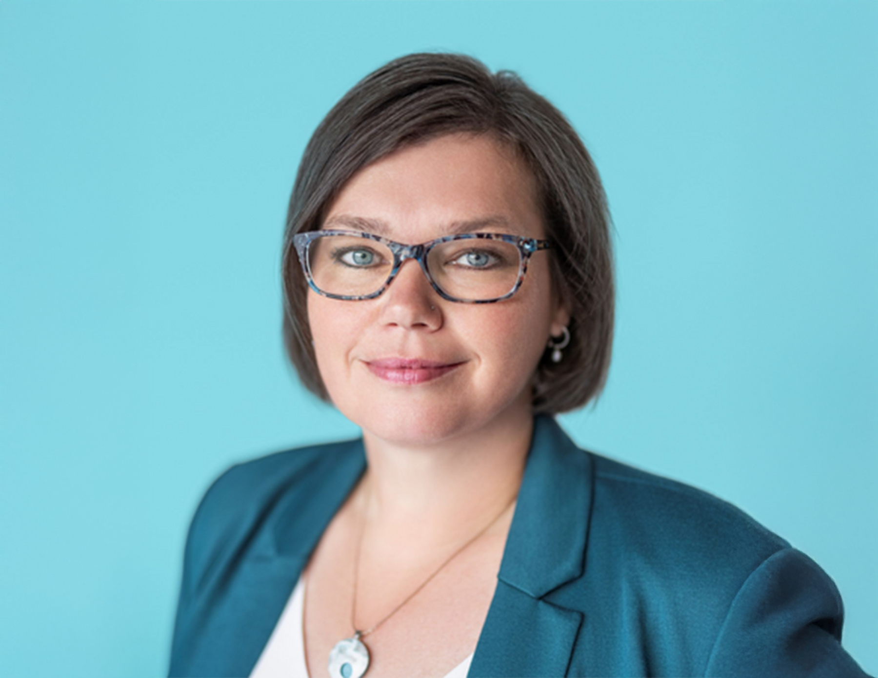 A woman wearing glasses, smiling at the camera.