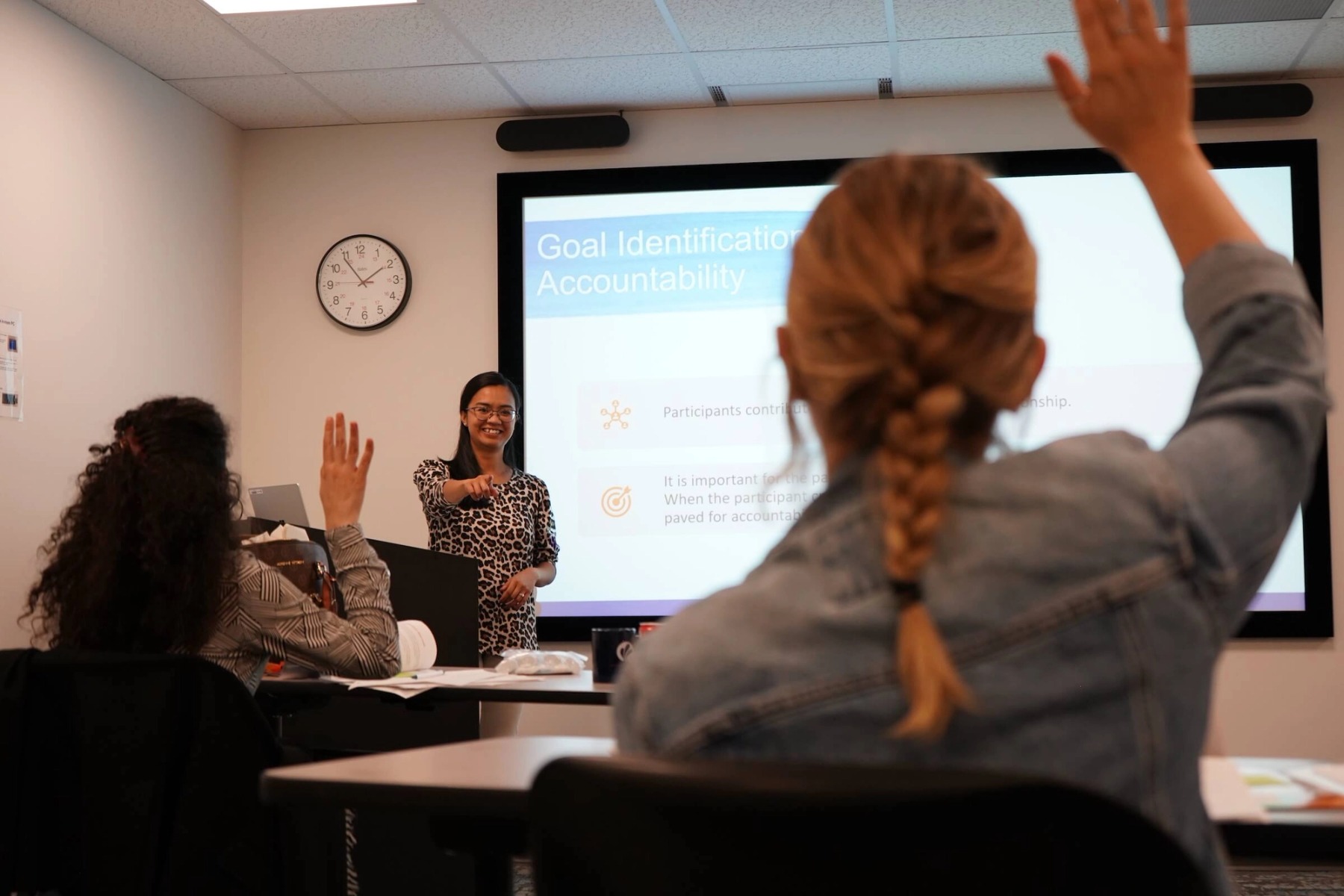 Two women raise their hands in a classroom.