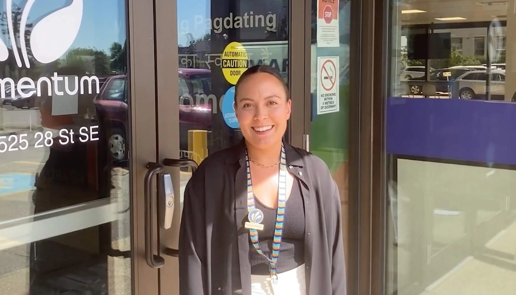 A woman wearing a Momentum badge stands in front of the organization's front door, prepared to record a video highlighting Momentum's career opportunities.