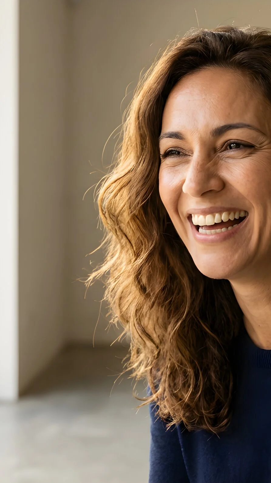 Woman with a genuine smile in natural light — representing the radiant, lifted results of biostimulation skin treatments.