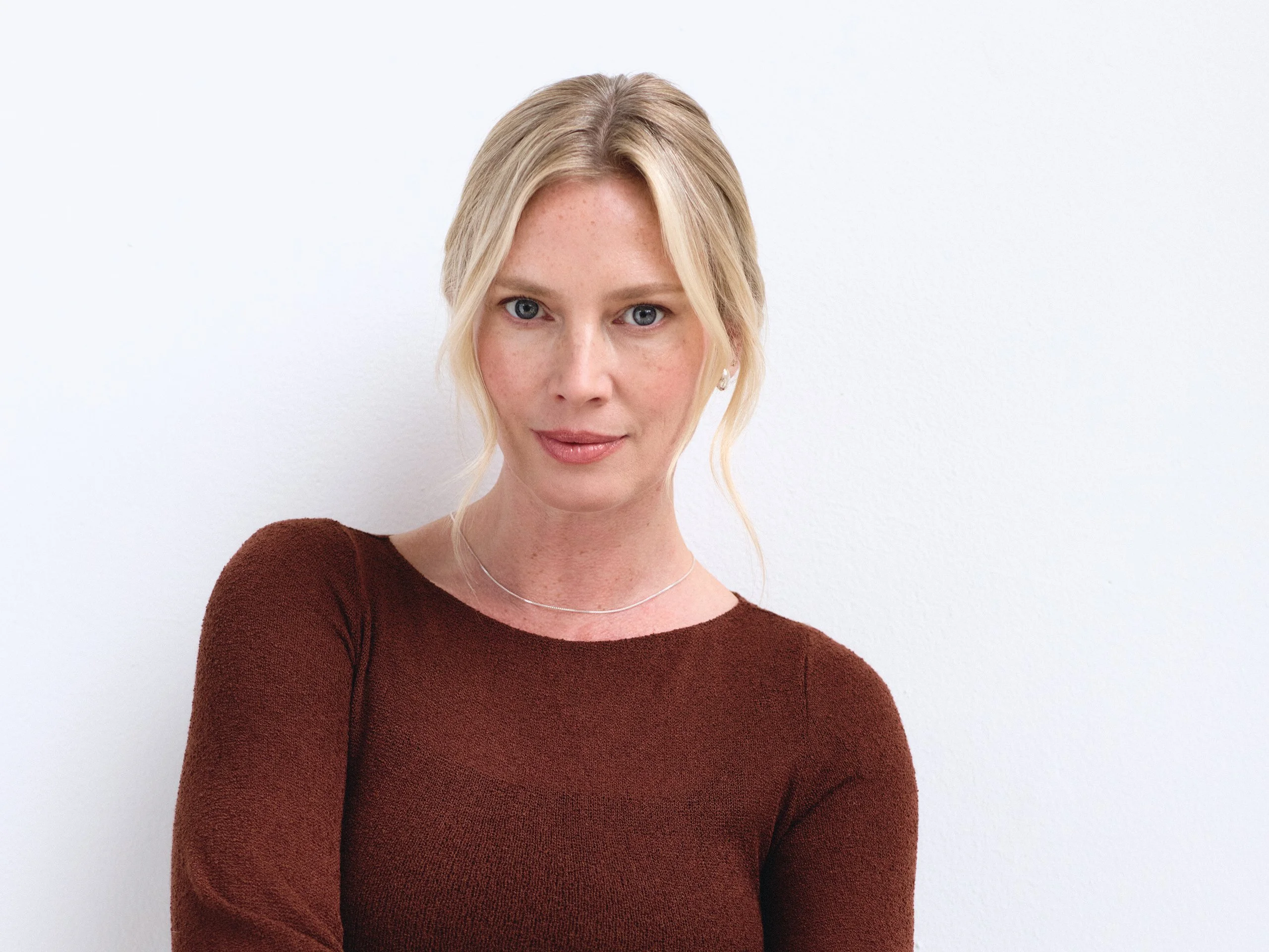 Ashley — arms crossed, gold cuff, composed studio portrait