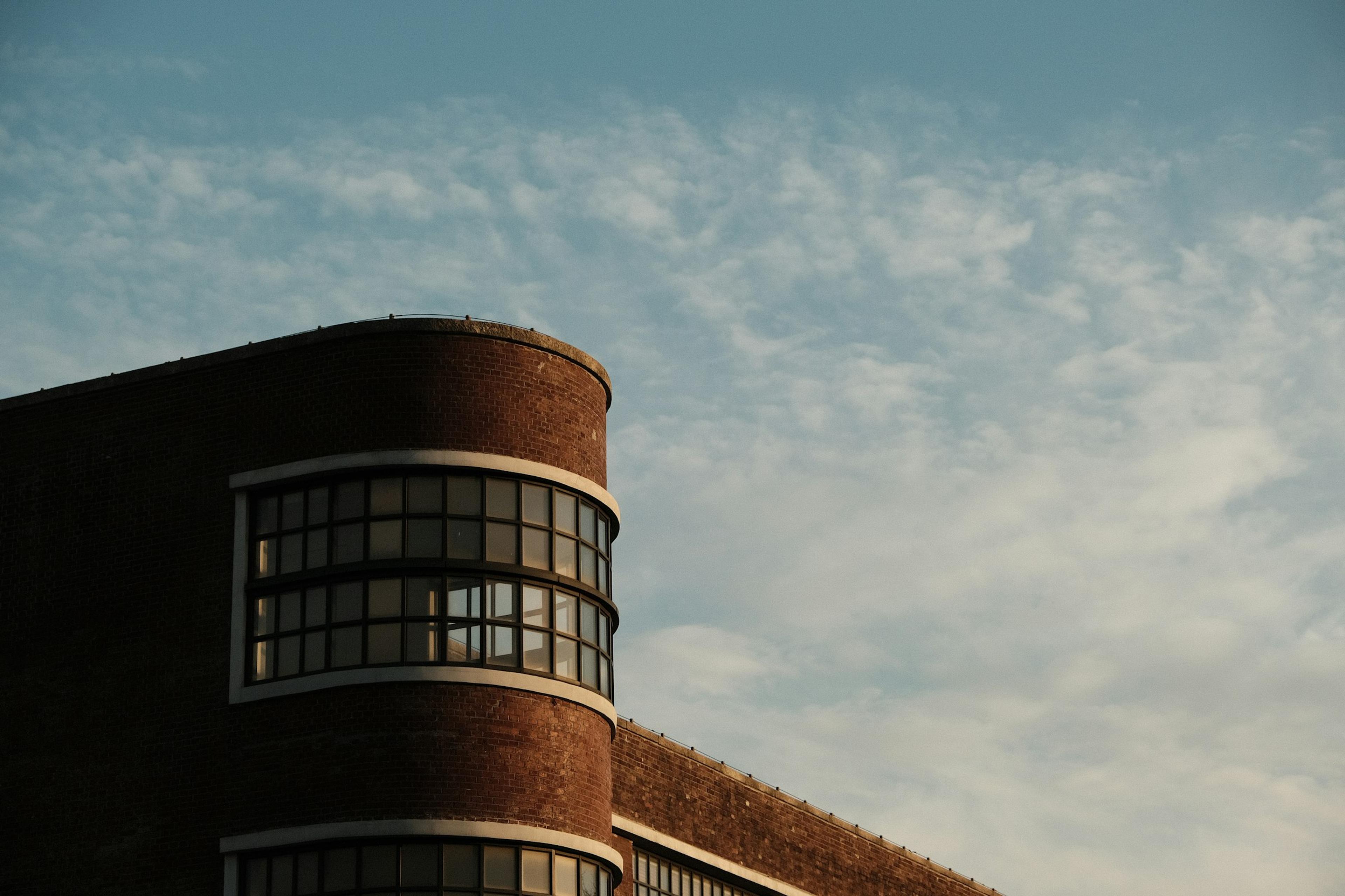 Curving brick building corner against a cloudy sky