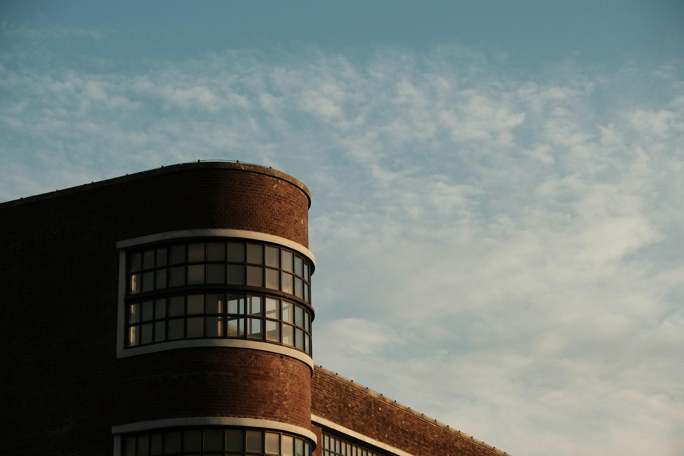 Curving brick building corner against a cloudy sky