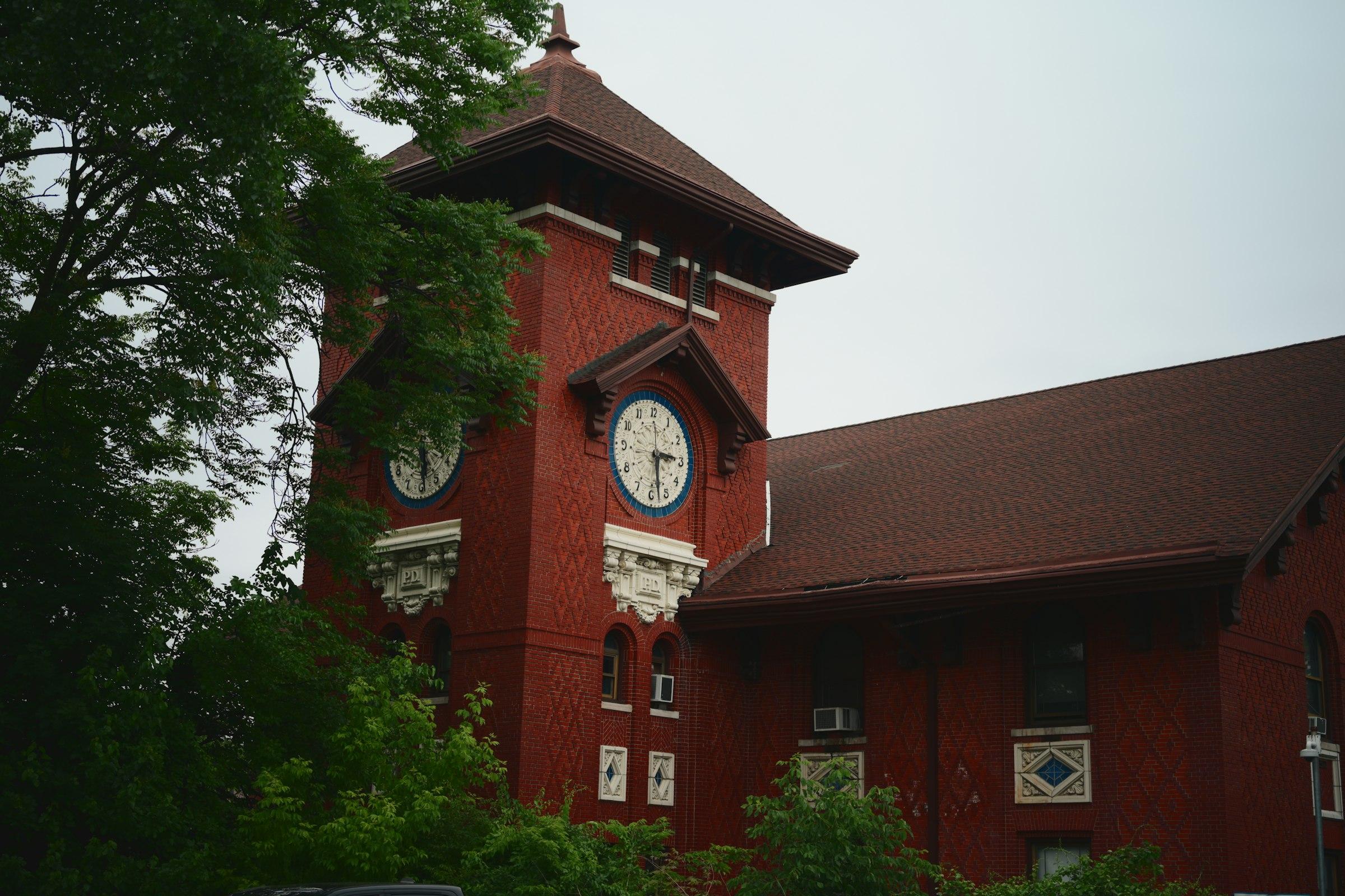 A red brick building with a clock tower framed by trees