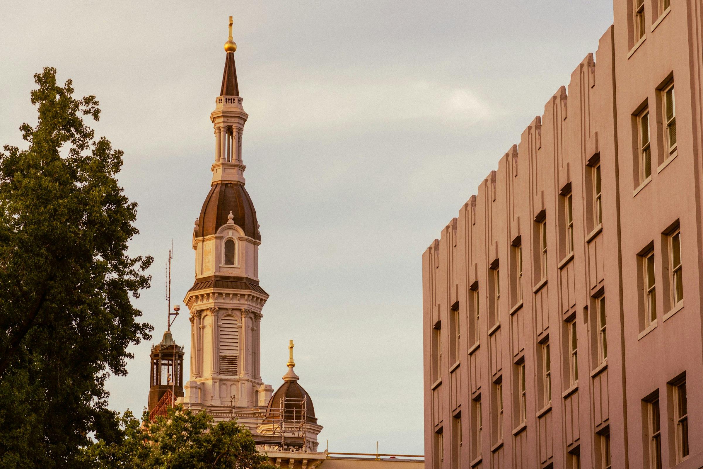 A church steeple beside a modern building at golden hour