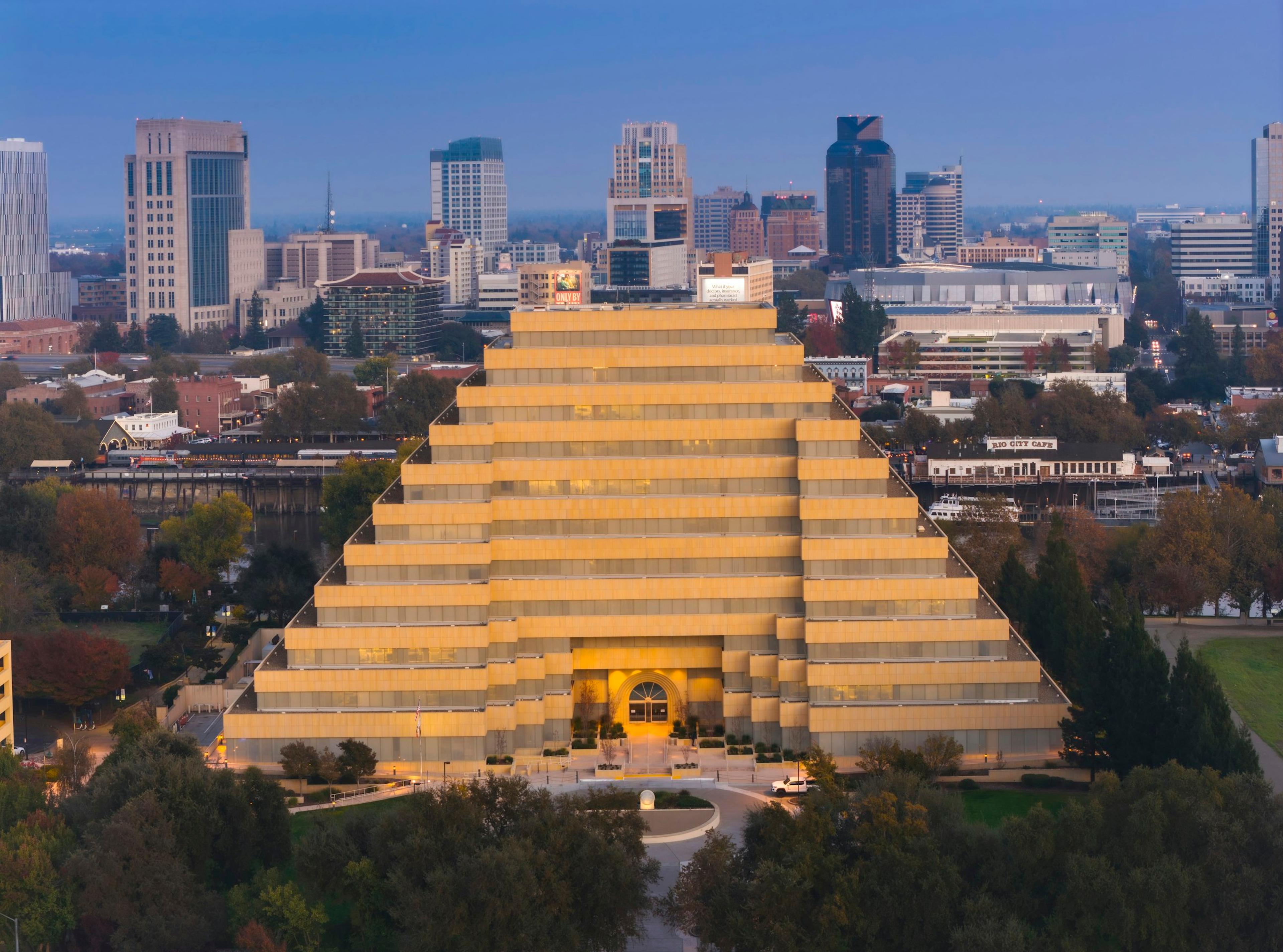 A pyramid-form building in a city skyline at dusk