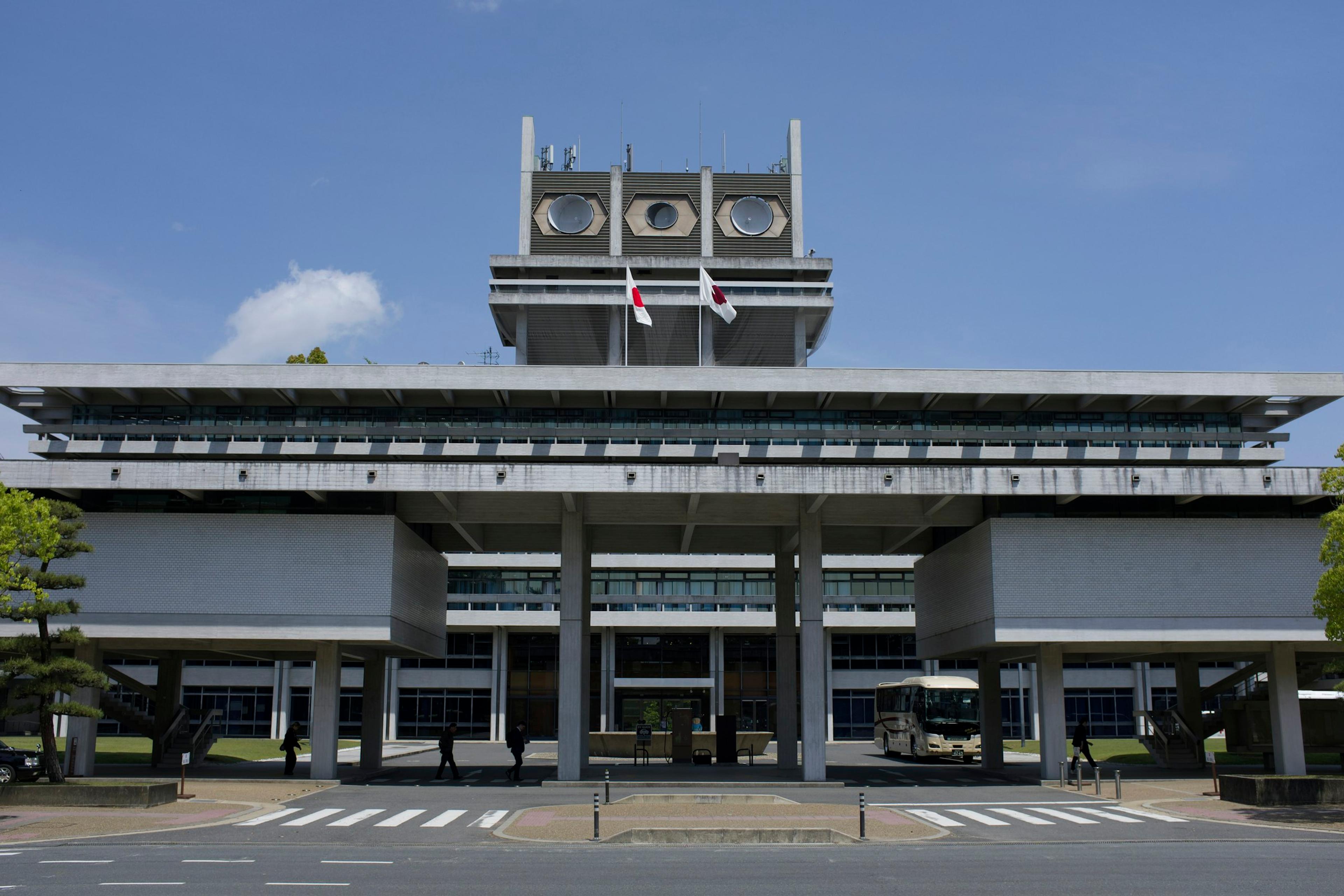 Modern grey building with flags under a clear blue sky